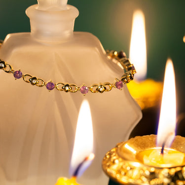 Elegant 18k yellow gold bracelet with natural alexandrite and diamond floral links displayed near candlelight